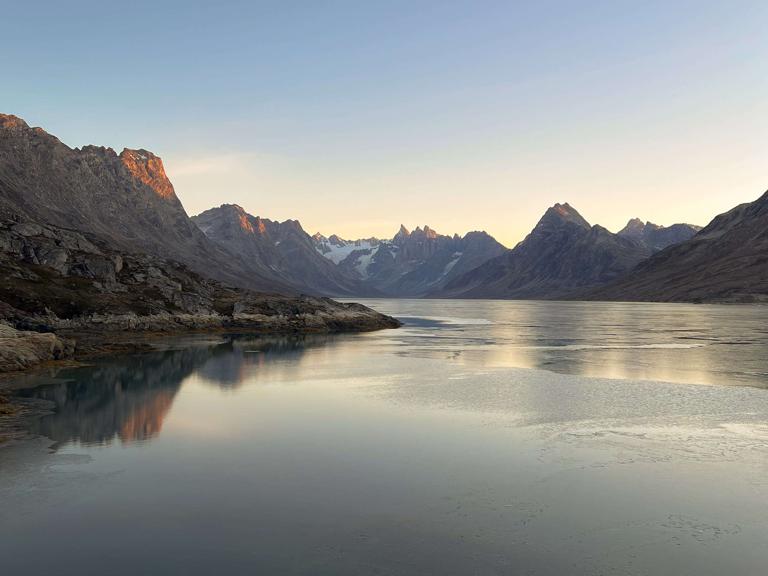 Evening light over the fjord beneath sharp peaks
